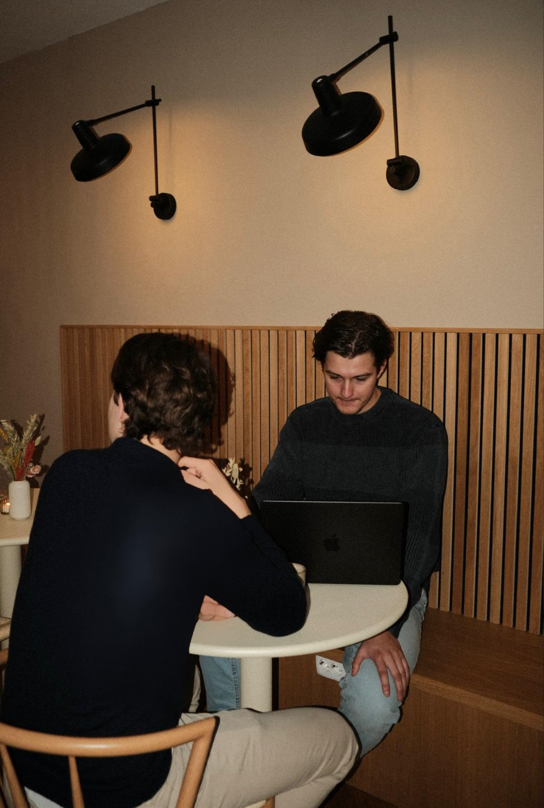 Two people sitting at a table with a laptop